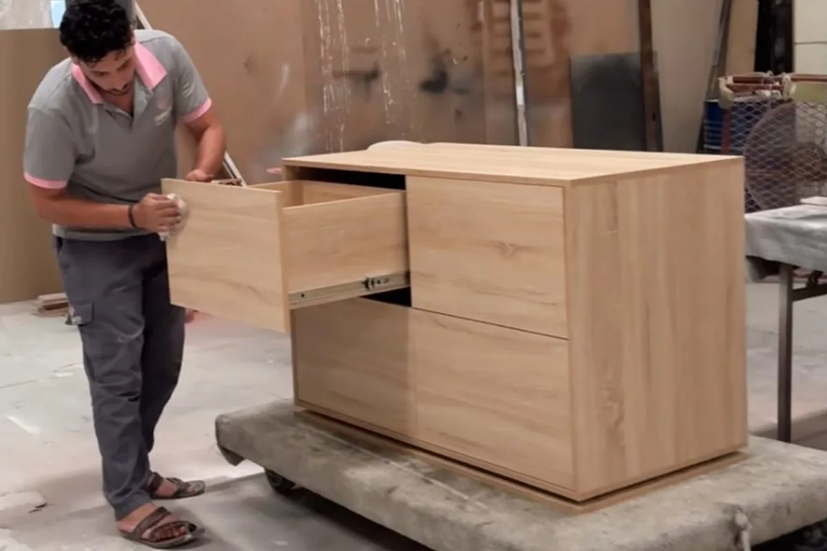 Technician fitting drawers to a finished wooden cabinet before dispatch at the Olympic Furniture factory in Dubai