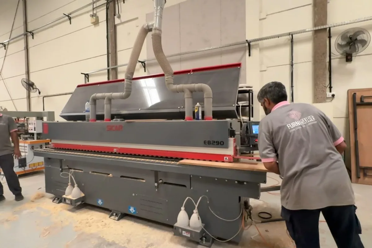 Automatic edge banding machine sealing panel edges at the Olympic Furniture factory in Dubai