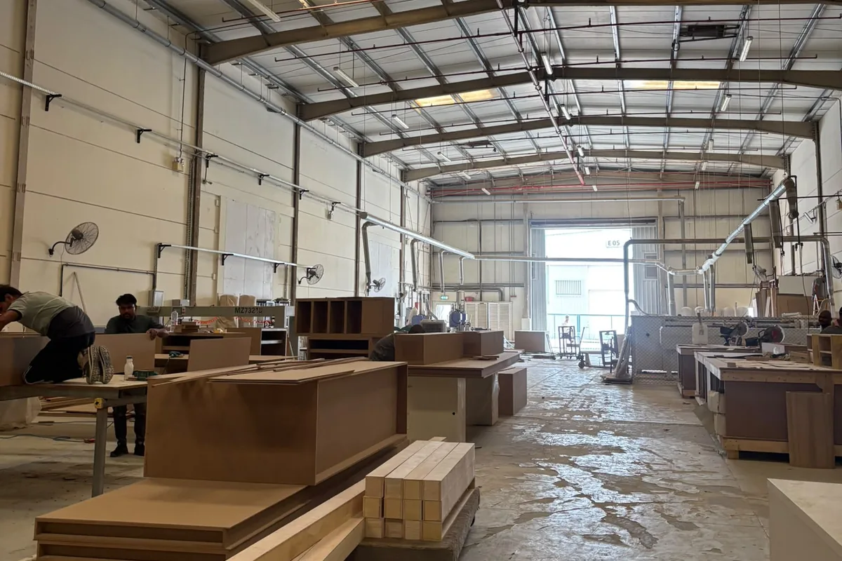 Workers building wardrobe and cabinet carcasses on the joinery benches at the Olympic Furniture factory in Dubai